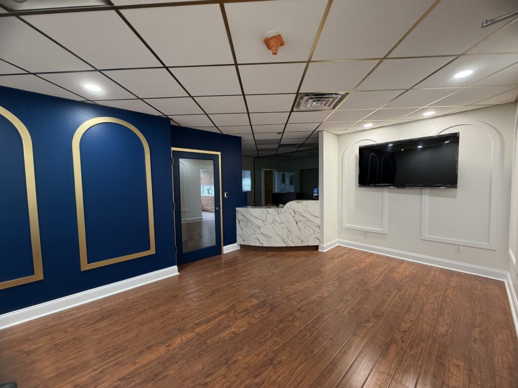Dental office reception in Scarsdale NY with new front desk, arched wall panels and navy accent wall built by GCMM Dental Construction
